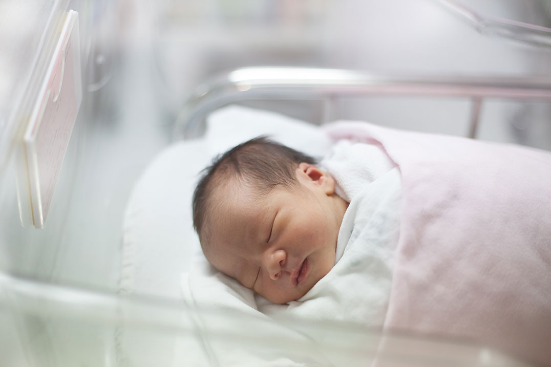 Newborn baby fast asleep in a hospital blanket