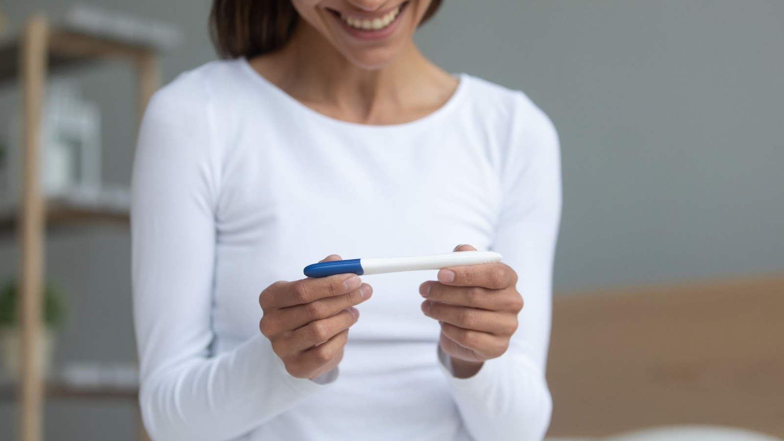 Woman sit indoors close up focus on hands holding pregnancy test, waiting for results.